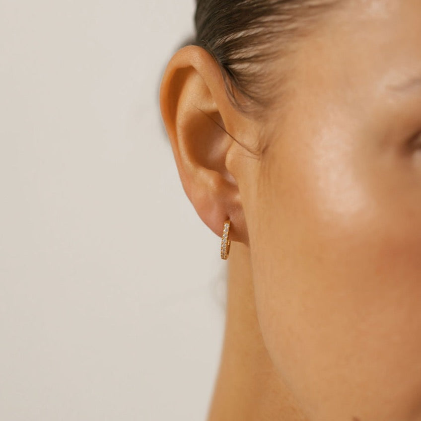 a woman is wearing tiny pave hoop earrings made in Canada