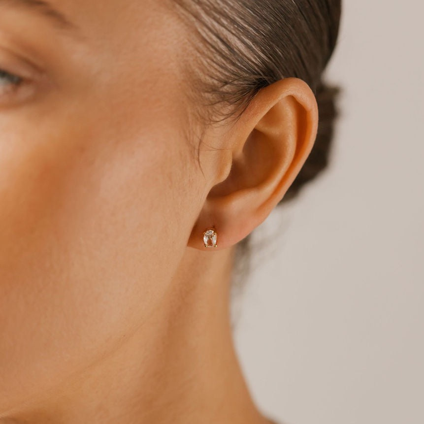 a woman is wearing a gold white topaz oval stud made in Canada