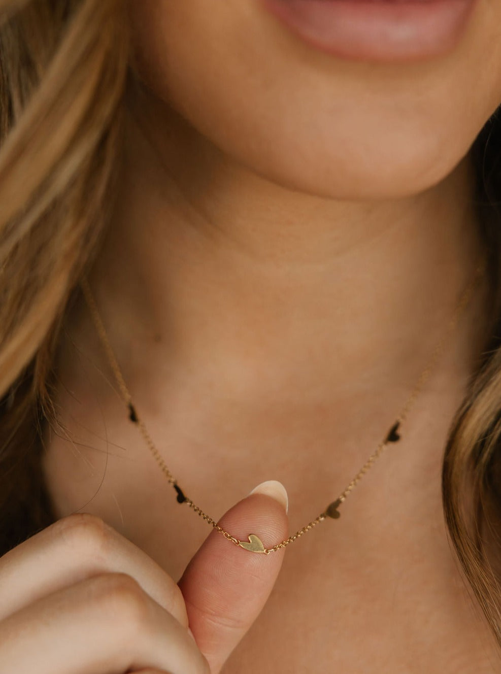 a women is wearing a dainty heart pendant necklace 