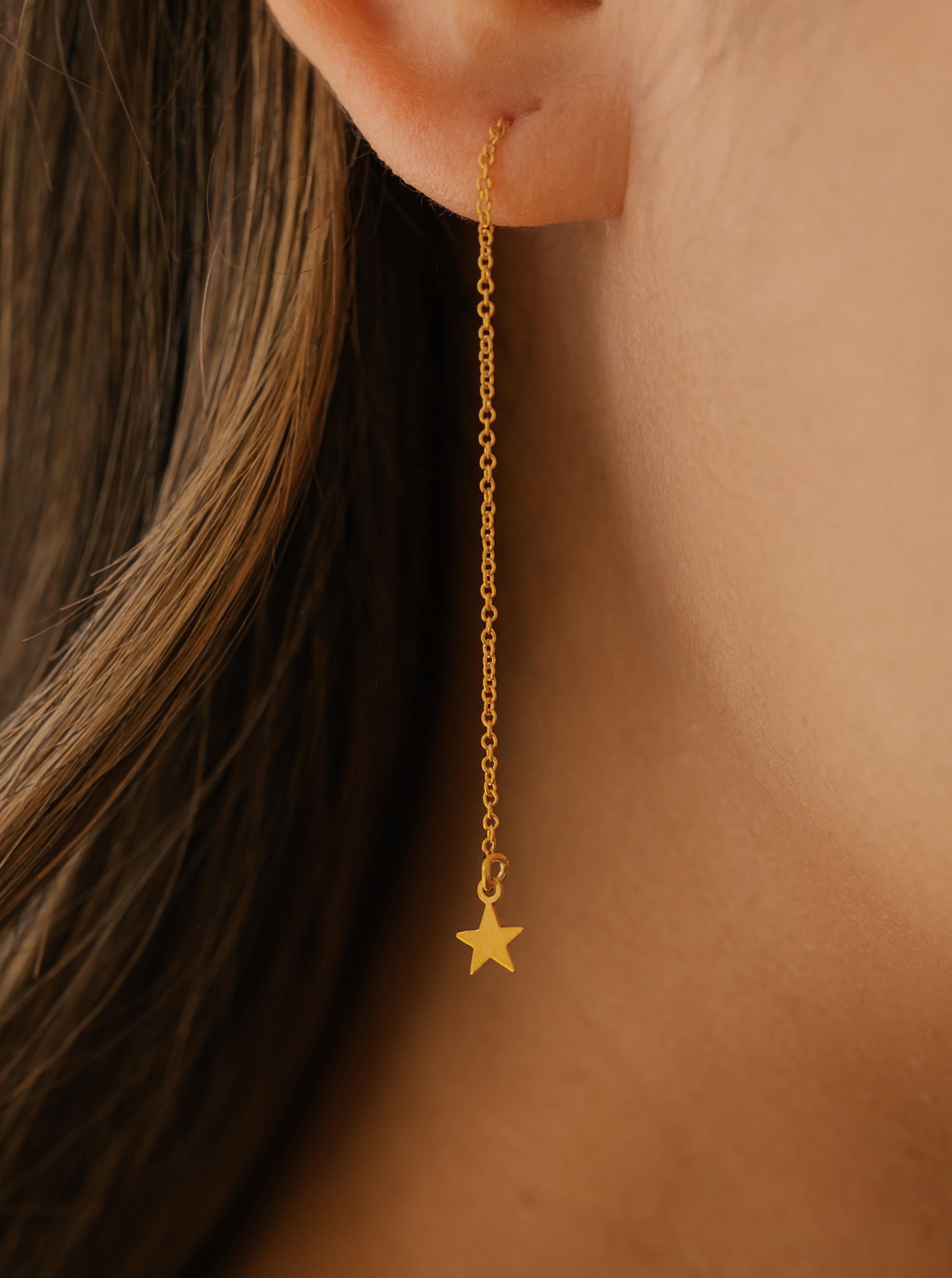 a woman is wearing gold star earrings made in Canada
