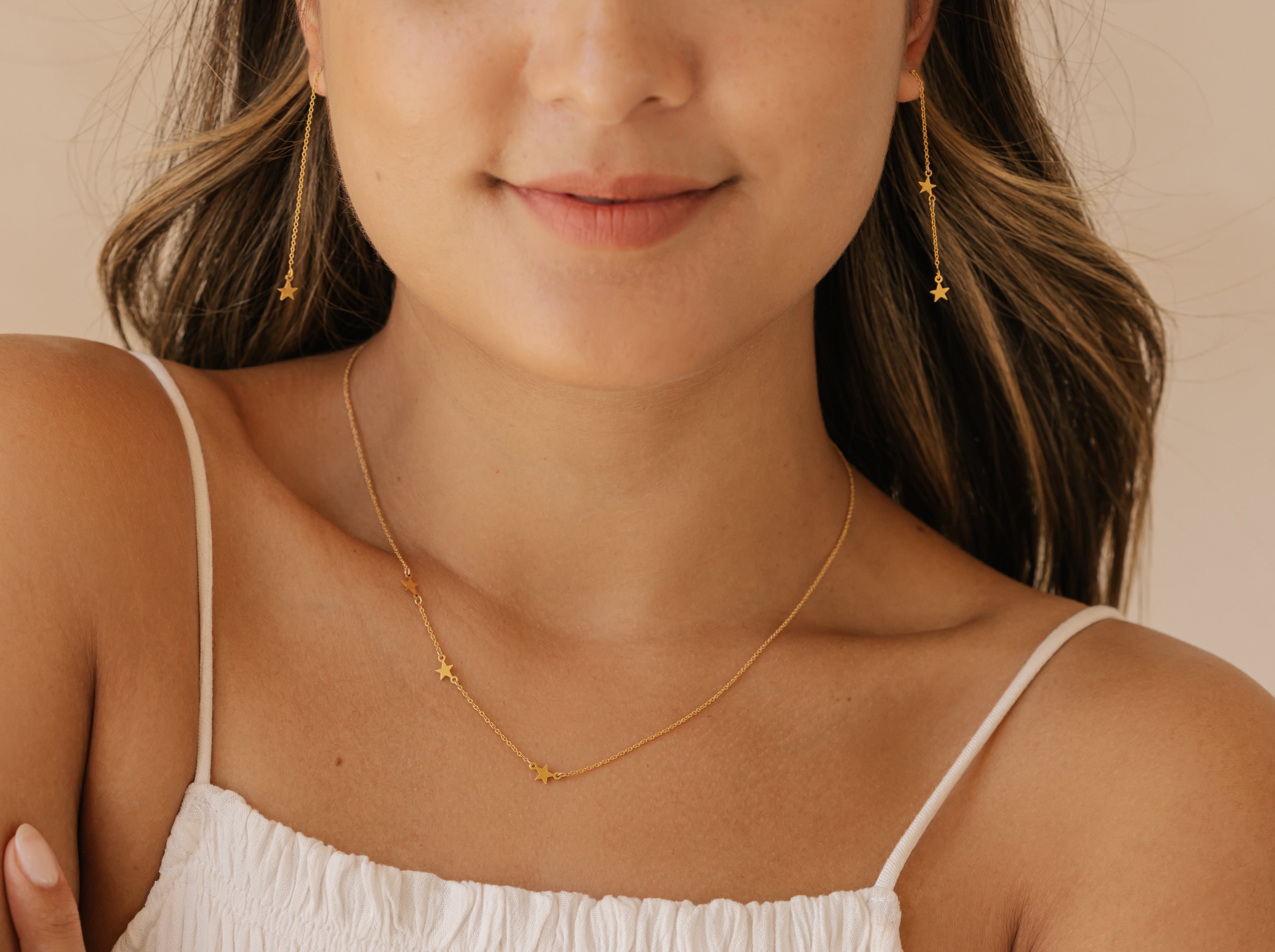 a woman is wearing gold vermel star earrings and a star necklace made in Edmonton
