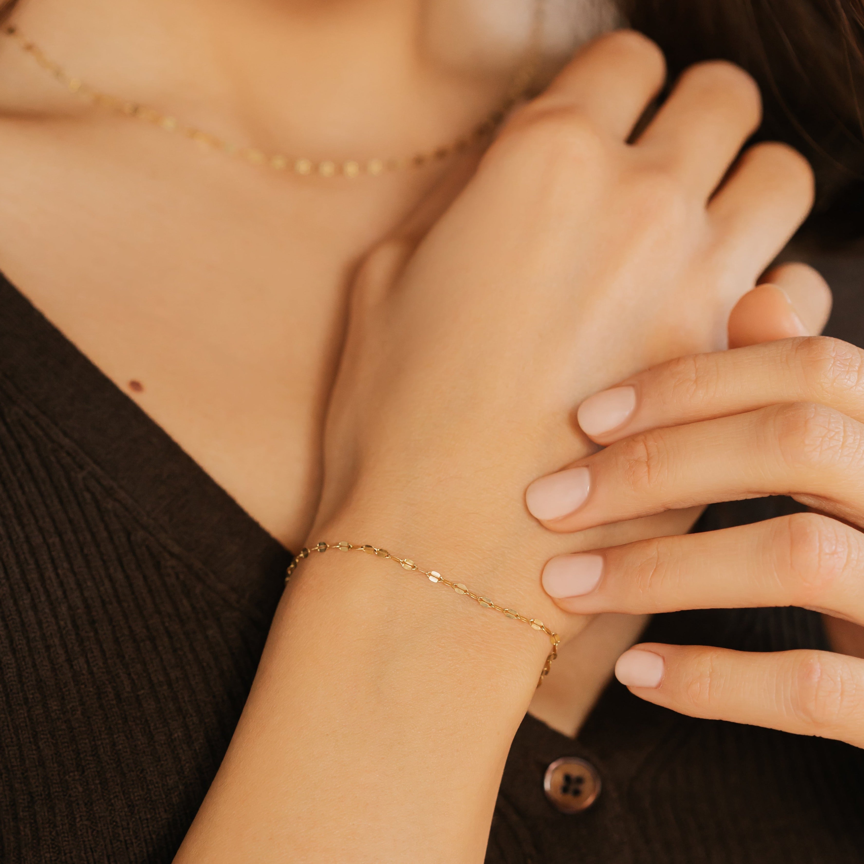 a woman is wearing a gold chain bracelet made in Canada