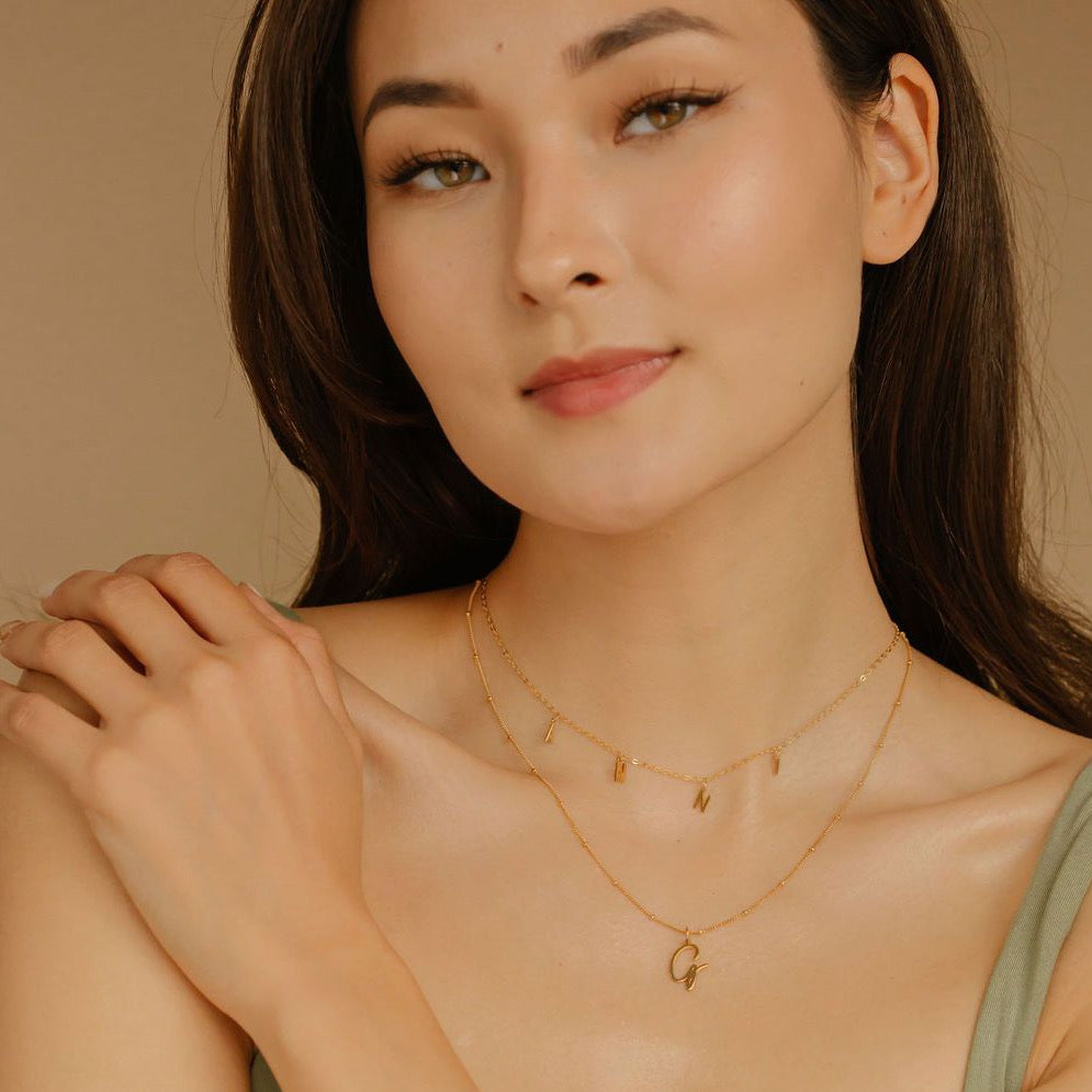 Model posing with Initial "G" Medium Charm Necklace layered with Custom Dangle Letter Necklace 