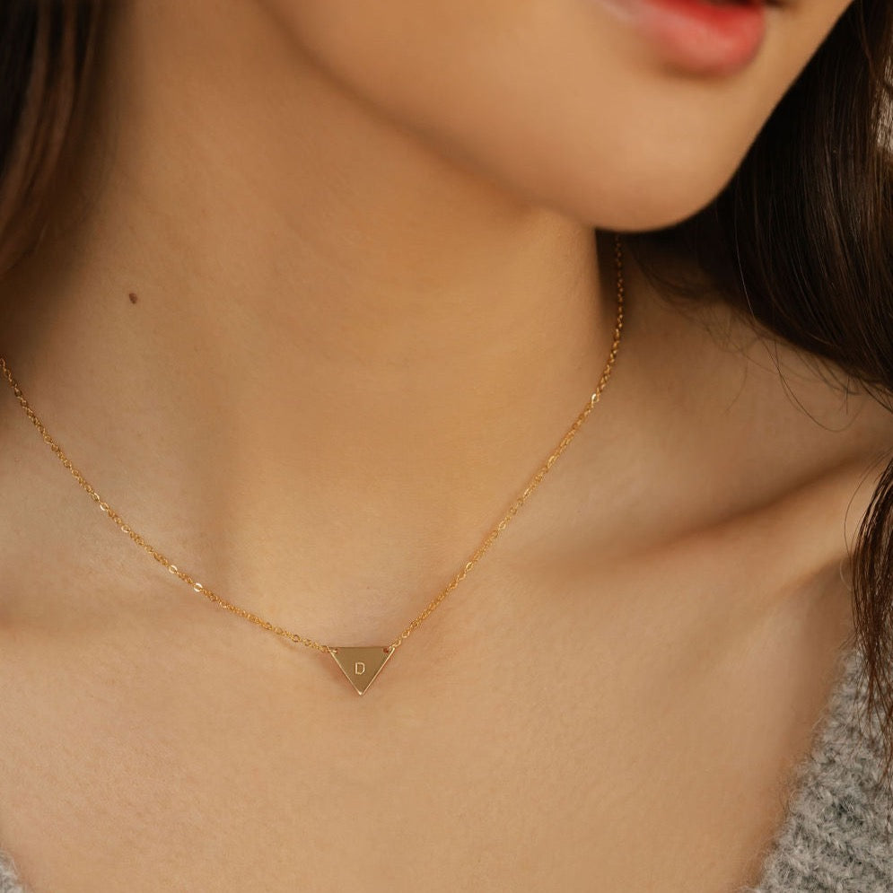a woman is wearing a triangle geometric pendant necklace made in Canada