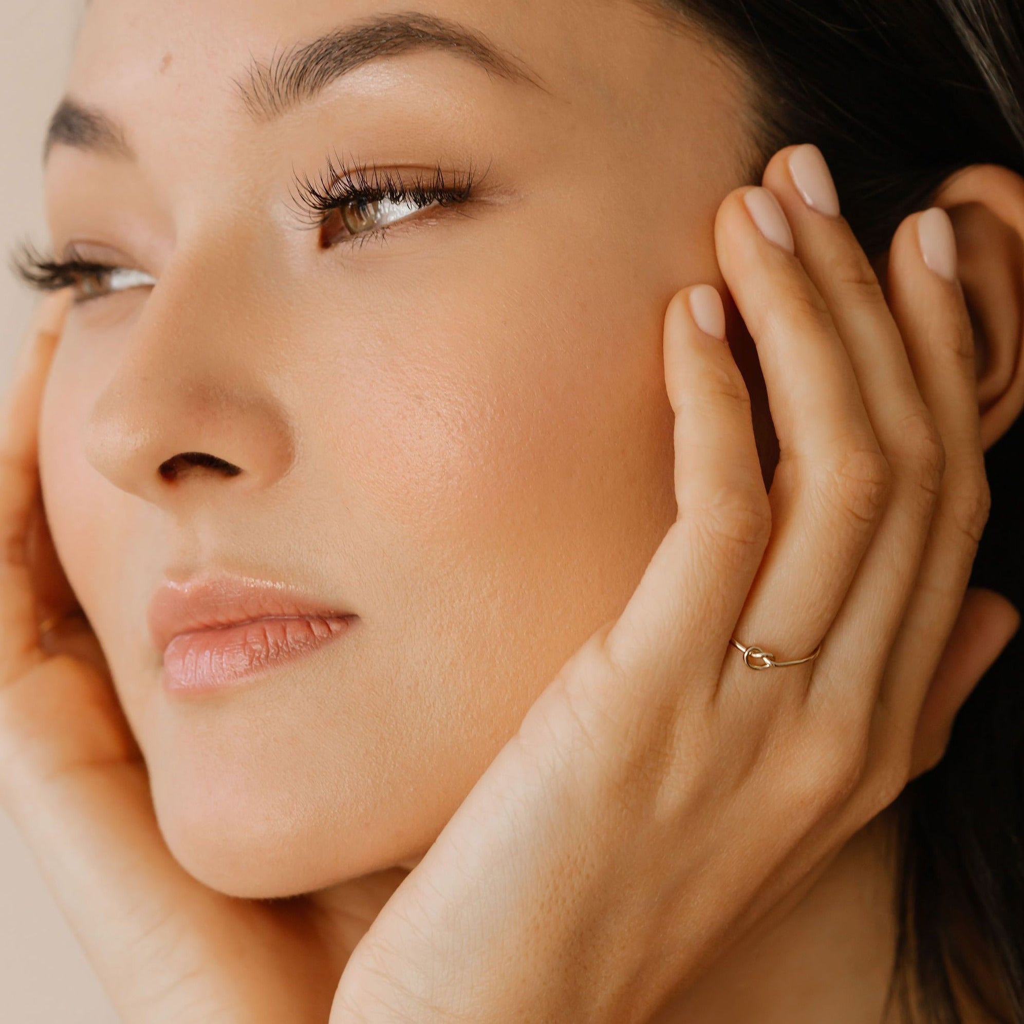 a woman is wearing a gold knot ring